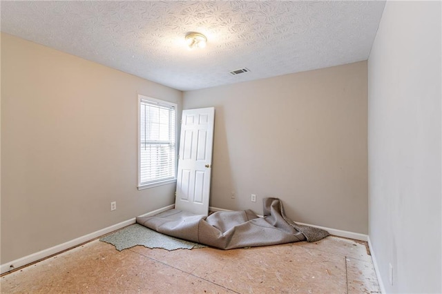 unfurnished room with a textured ceiling