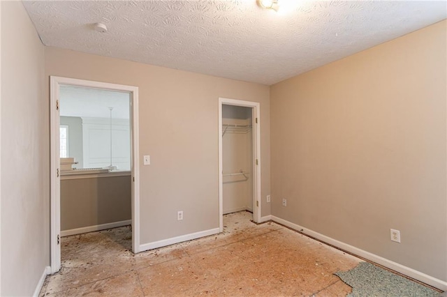 unfurnished bedroom with a textured ceiling, a spacious closet, and a closet