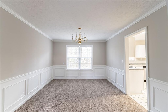 carpeted spare room featuring a textured ceiling, an inviting chandelier, and crown molding