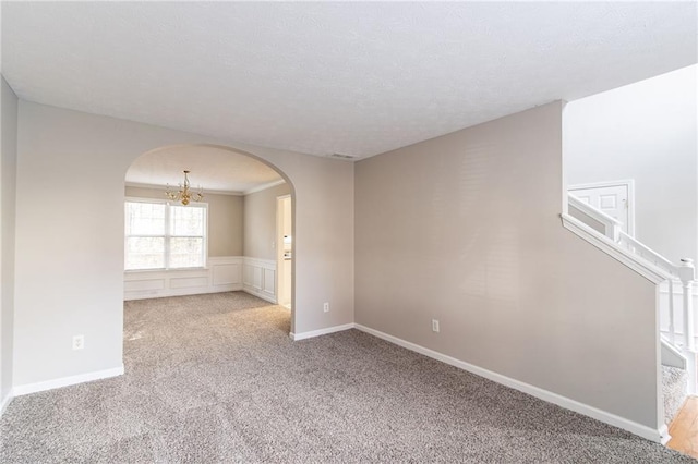 spare room with light carpet and a notable chandelier