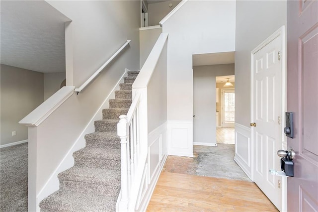 stairway with hardwood / wood-style floors and ceiling fan