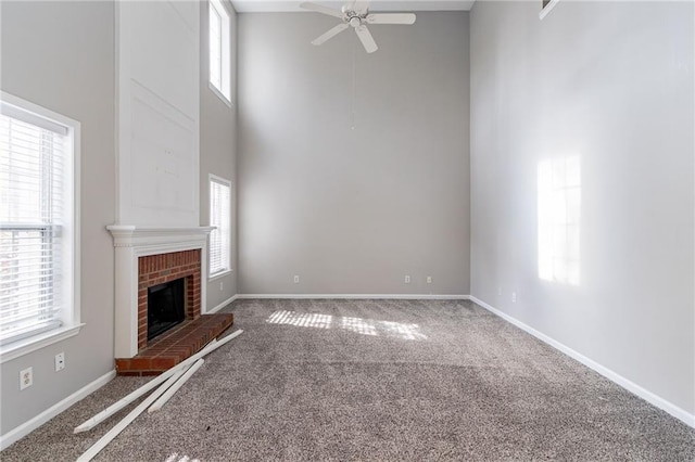 unfurnished living room with carpet, a high ceiling, ceiling fan, and a healthy amount of sunlight