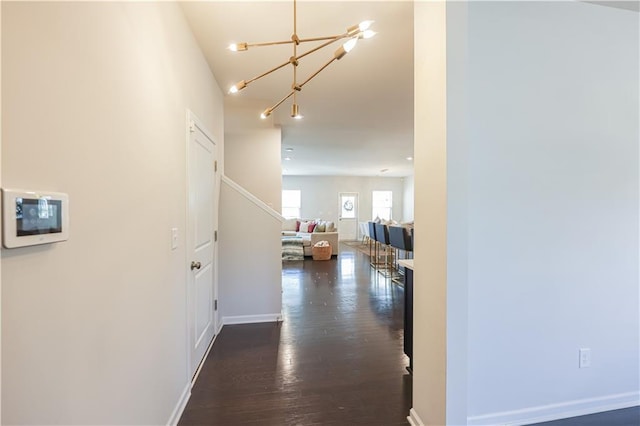 hallway featuring dark wood-type flooring and a chandelier