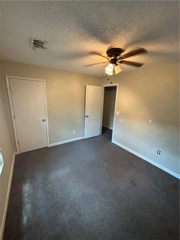 1182 Sims St SW, Atlanta, GA 30310 - unfurnished bedroom with baseboards, a textured ceiling, dark colored carpet, and a ceiling fan
