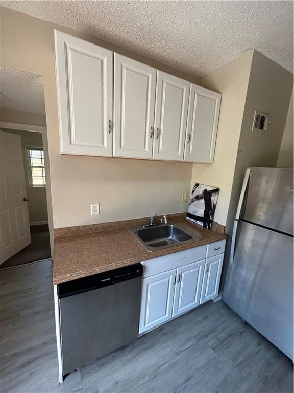 1182 Sims St SW, Atlanta, GA 30310 - kitchen featuring appliances with stainless steel finishes, a sink, a textured ceiling, wood finished floors, and white cabinets