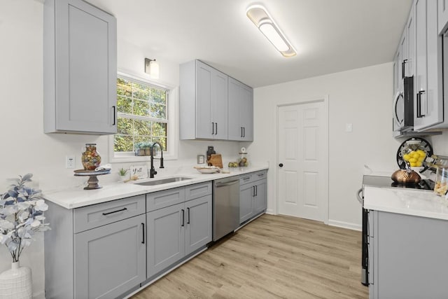 kitchen with stainless steel appliances, light hardwood / wood-style flooring, gray cabinetry, and sink