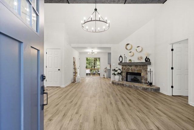 living room featuring a fireplace, a towering ceiling, light hardwood / wood-style floors, and a notable chandelier