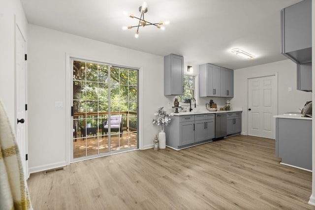 kitchen featuring stainless steel dishwasher, gray cabinets, light wood-type flooring, and a chandelier