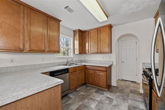 kitchen featuring visible vents, brown cabinetry, arched walkways, appliances with stainless steel finishes, and a sink