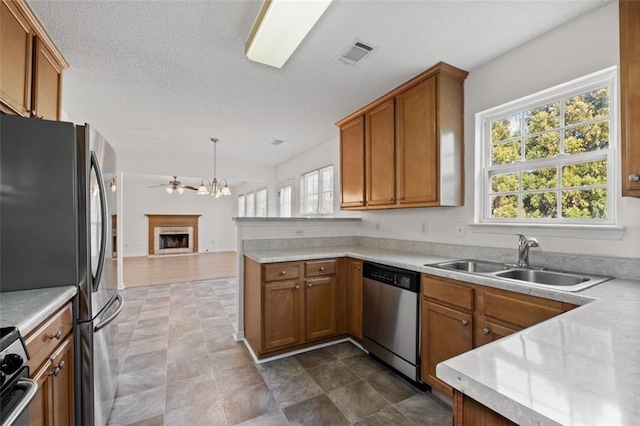 kitchen with stainless steel appliances, brown cabinetry, visible vents, and a sink