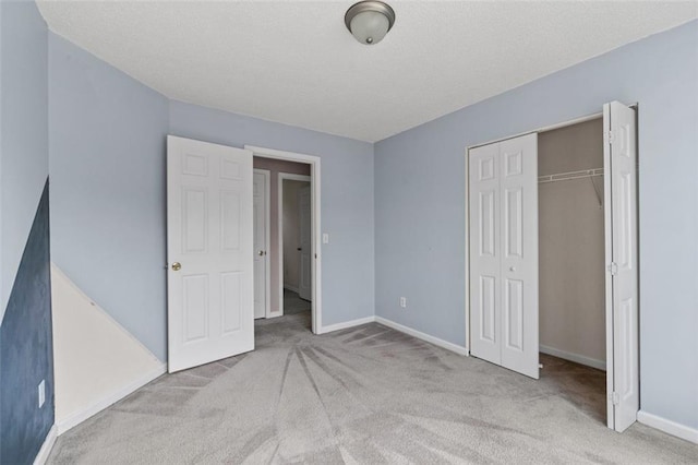 unfurnished bedroom featuring a textured ceiling, a closet, baseboards, and carpet flooring