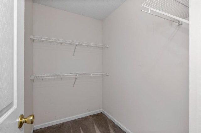 spacious closet featuring dark carpet