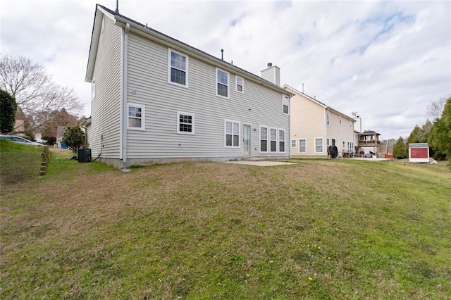 rear view of property with a chimney, central AC unit, a patio, and a yard