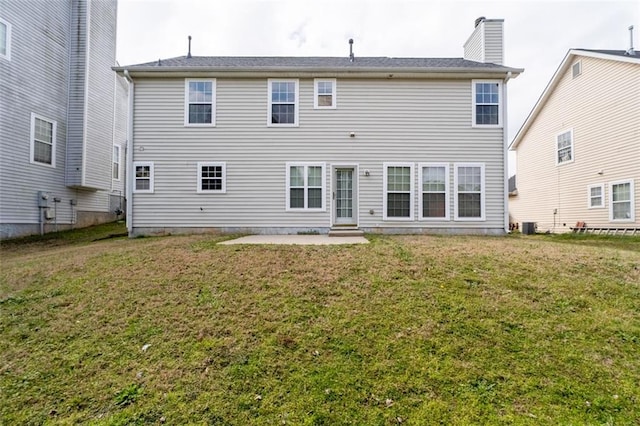 back of house with a patio area, a yard, and a chimney