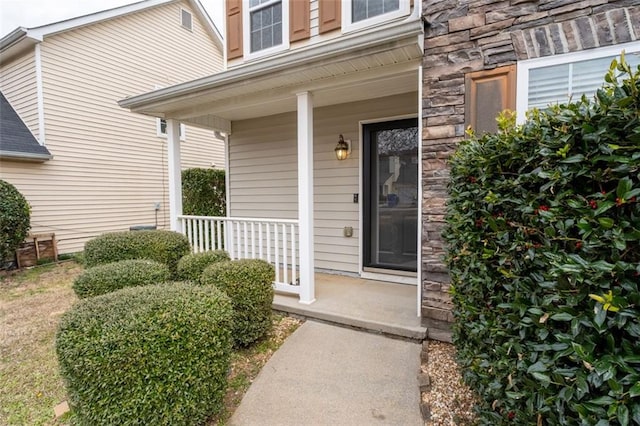 doorway to property with covered porch and stone siding