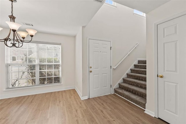 entryway with visible vents, baseboards, stairs, light wood-type flooring, and an inviting chandelier