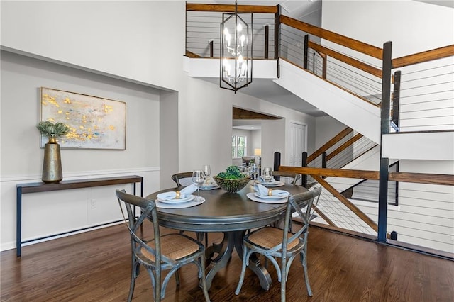 dining space with a chandelier, stairs, a towering ceiling, and wood finished floors