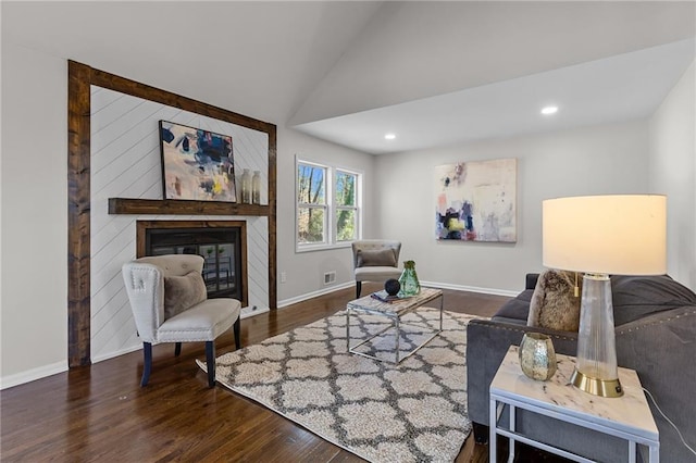 living area featuring lofted ceiling, a glass covered fireplace, wood finished floors, recessed lighting, and baseboards