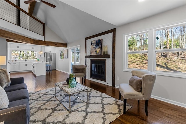 living area with a wealth of natural light, a glass covered fireplace, and dark wood finished floors