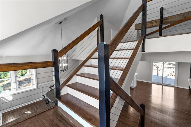 stairway featuring a wealth of natural light, a chandelier, baseboards, and wood finished floors