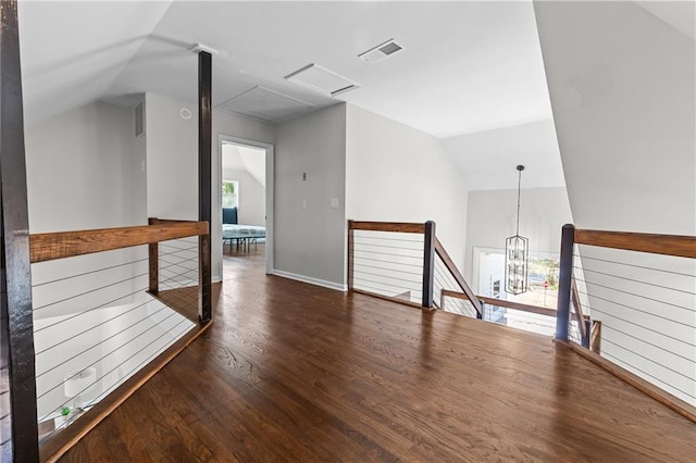 interior space with visible vents, a chandelier, attic access, lofted ceiling, and wood finished floors