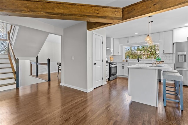 kitchen featuring tasteful backsplash, a kitchen island, appliances with stainless steel finishes, white cabinets, and dark wood-style flooring