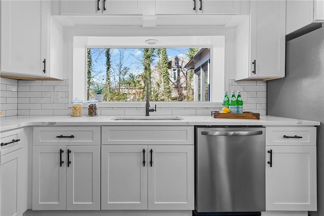 kitchen featuring backsplash, light stone counters, white cabinets, stainless steel appliances, and a sink