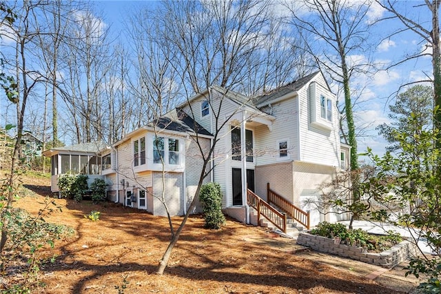 exterior space featuring brick siding, entry steps, and a sunroom