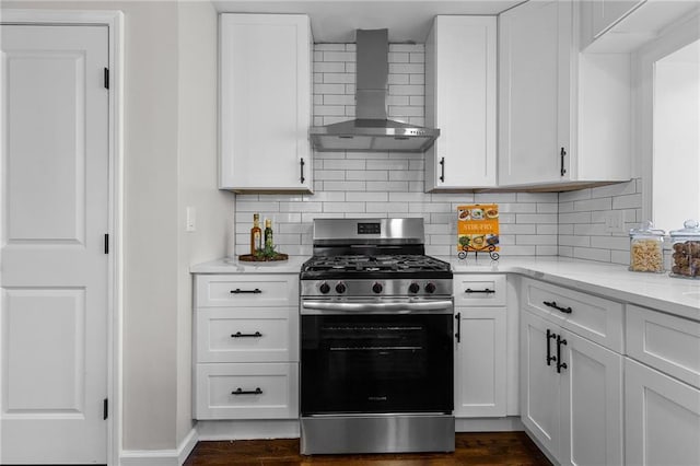 kitchen featuring stainless steel gas stove, decorative backsplash, white cabinets, and wall chimney range hood