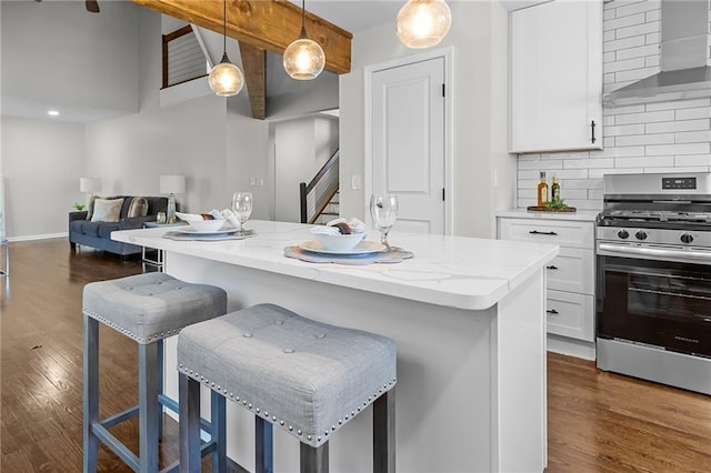 kitchen featuring dark wood-style floors, gas stove, decorative backsplash, white cabinetry, and wall chimney range hood