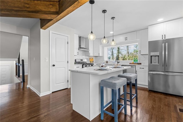 kitchen featuring dark wood finished floors, stainless steel appliances, light countertops, white cabinets, and wall chimney range hood