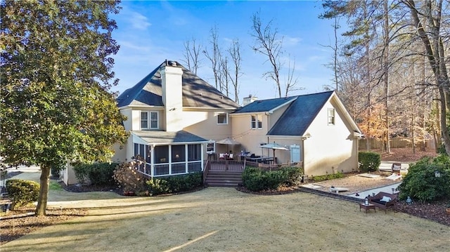 rear view of house with a wooden deck, a yard, and a sunroom