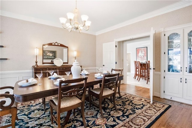 dining area with wood-type flooring, a chandelier, and crown molding