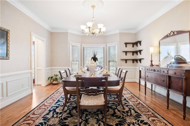 dining room with an inviting chandelier, ornamental molding, and light hardwood / wood-style floors