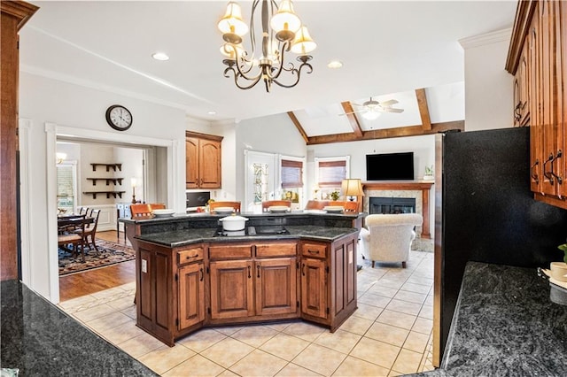 kitchen featuring light tile patterned flooring, a fireplace, decorative light fixtures, and ceiling fan with notable chandelier