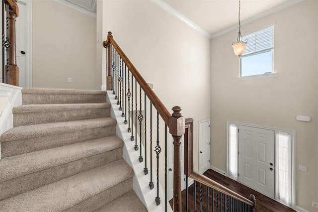 entryway featuring crown molding, baseboards, stairway, and a towering ceiling