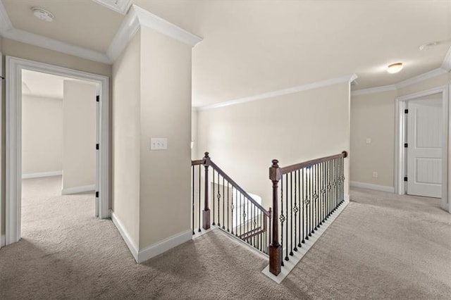hall featuring baseboards, ornamental molding, carpet, and an upstairs landing