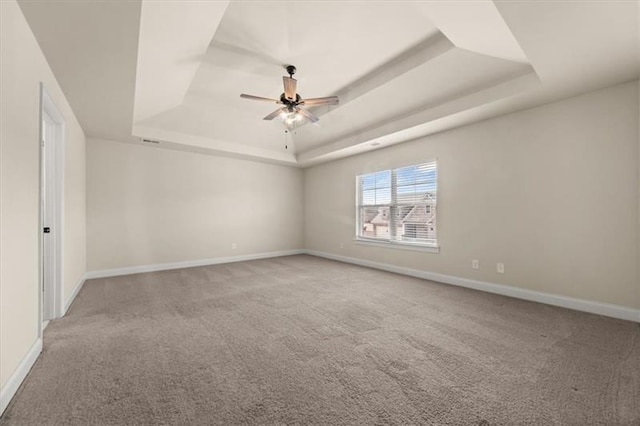 unfurnished room featuring carpet floors, baseboards, a ceiling fan, and a tray ceiling