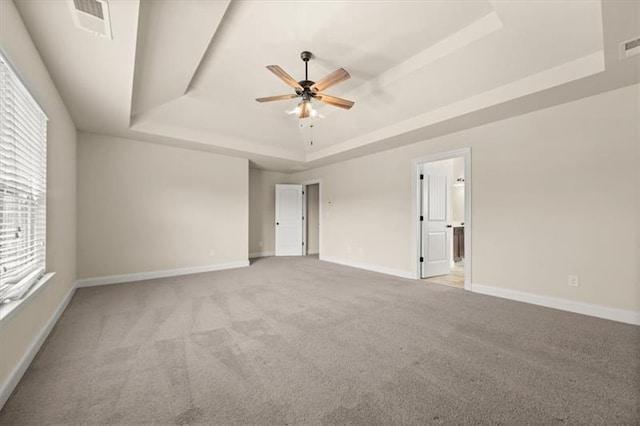carpeted empty room featuring baseboards, a raised ceiling, ceiling fan, and visible vents