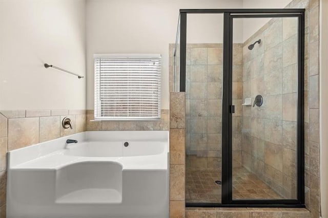 bathroom featuring wainscoting, a shower stall, and a garden tub