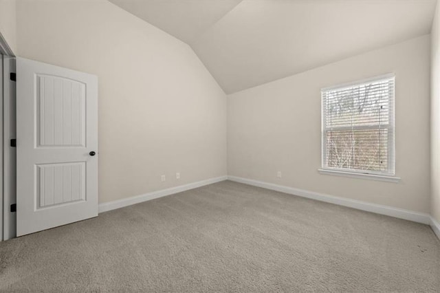 interior space featuring baseboards, light carpet, and vaulted ceiling