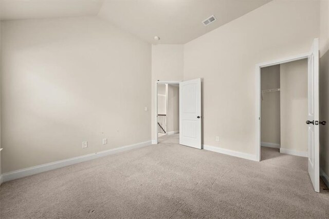 unfurnished bedroom featuring carpet floors, baseboards, lofted ceiling, visible vents, and a closet