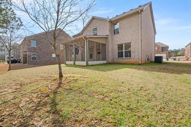 rear view of property with central air condition unit, a lawn, a sunroom, and brick siding
