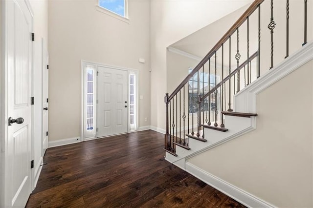foyer featuring baseboards, a high ceiling, stairs, and wood finished floors