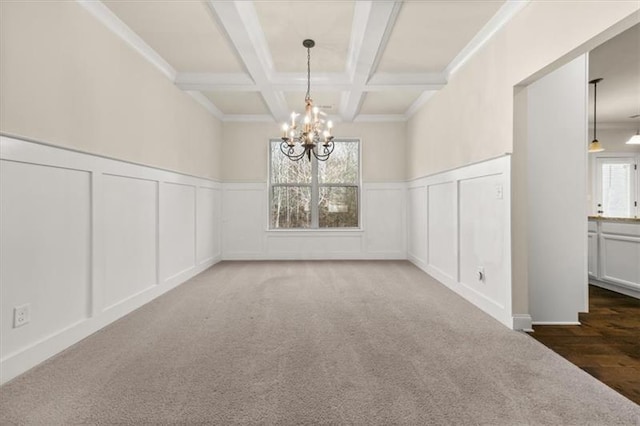 unfurnished dining area with beamed ceiling, coffered ceiling, a notable chandelier, and a decorative wall
