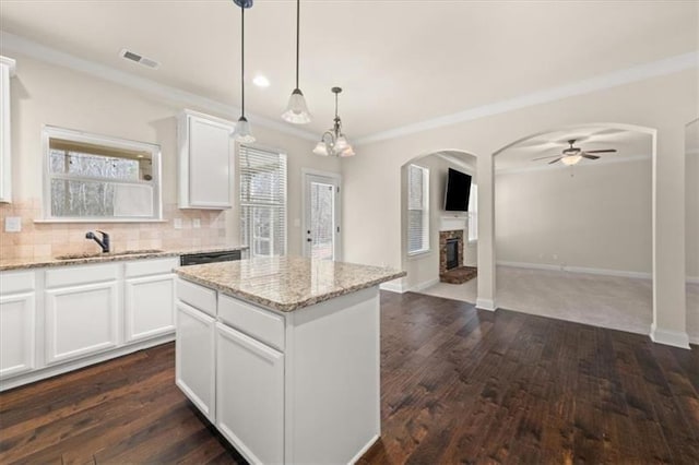 kitchen featuring ceiling fan, a sink, a center island, open floor plan, and visible vents