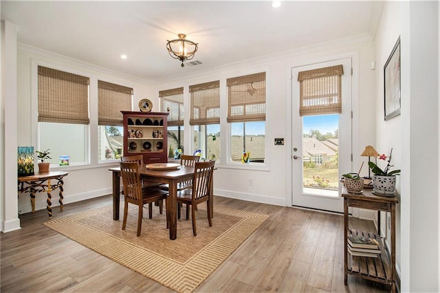 dining area with light wood-style floors, baseboards, plenty of natural light, and crown molding