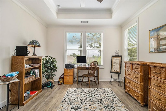 office area featuring ornamental molding, a tray ceiling, wood finished floors, and visible vents