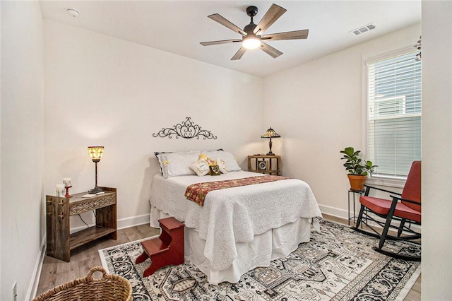 bedroom with baseboards, a ceiling fan, wood finished floors, and visible vents