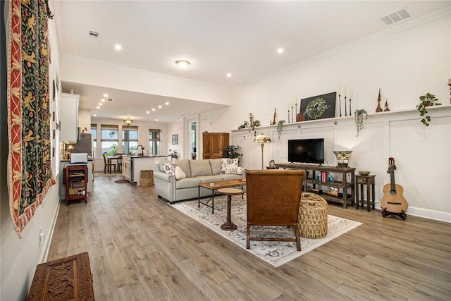 living room featuring visible vents, ornamental molding, light wood finished floors, and recessed lighting